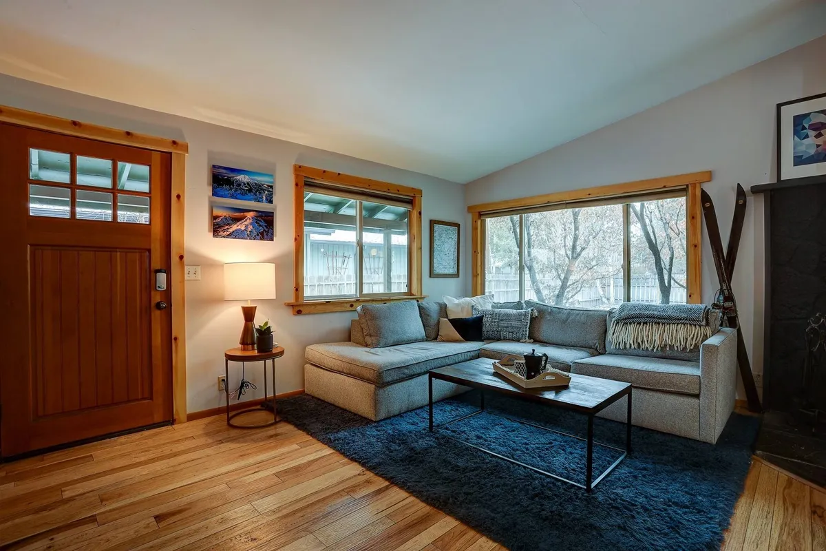 This interior image features a cozy living area with a sofa, coffee table, windows, and a visible doorway. The door and windows offer a glimpse of the outdoors, enhancing the feeling of transition from exterior adventures to interior comfort. The space is uncluttered, which hints at ample storage and a practical layout.